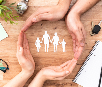 Hands surrounding a paper cut-out of a family